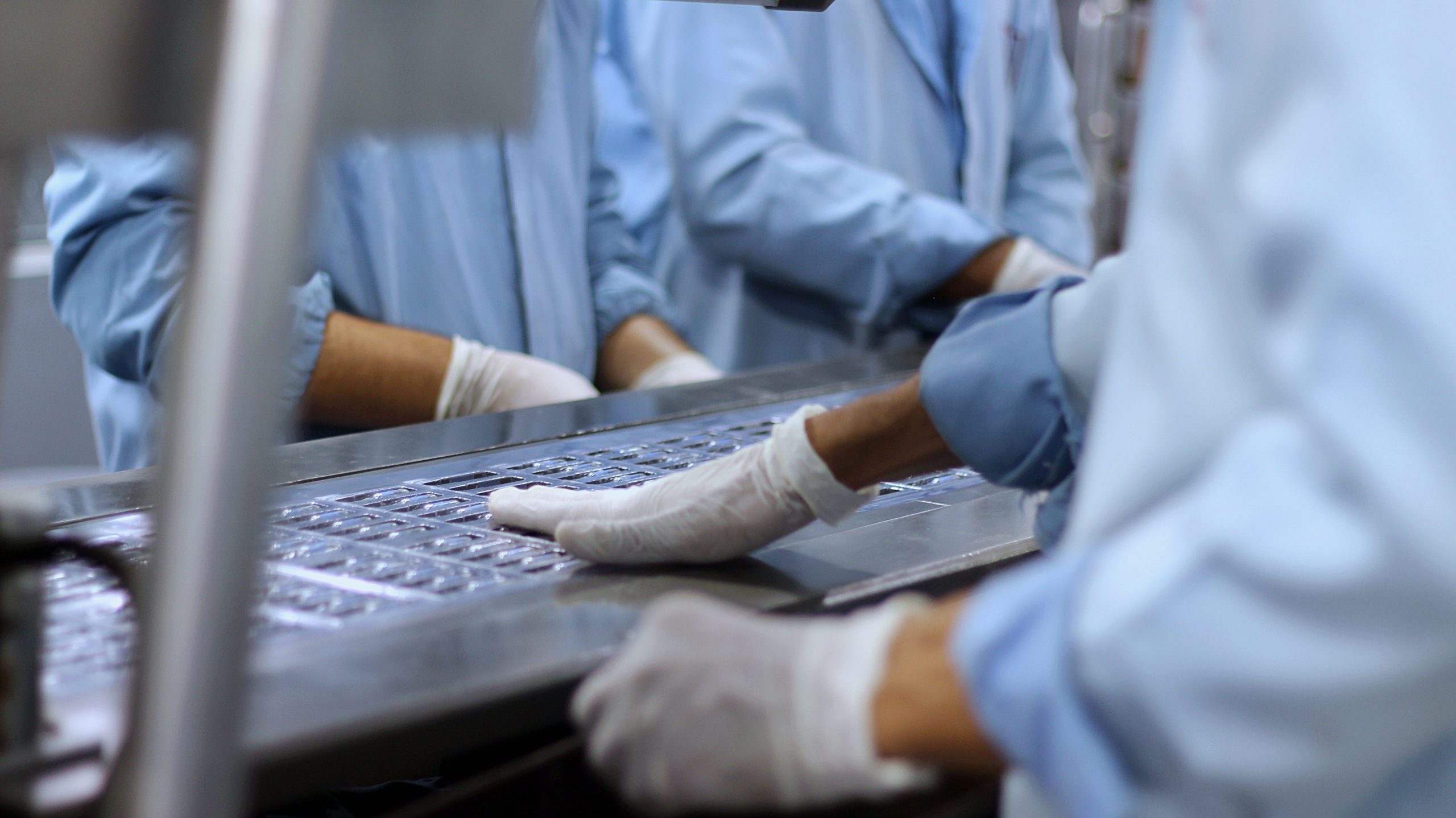 Pharmaceutical workers packaging tablets on a production line